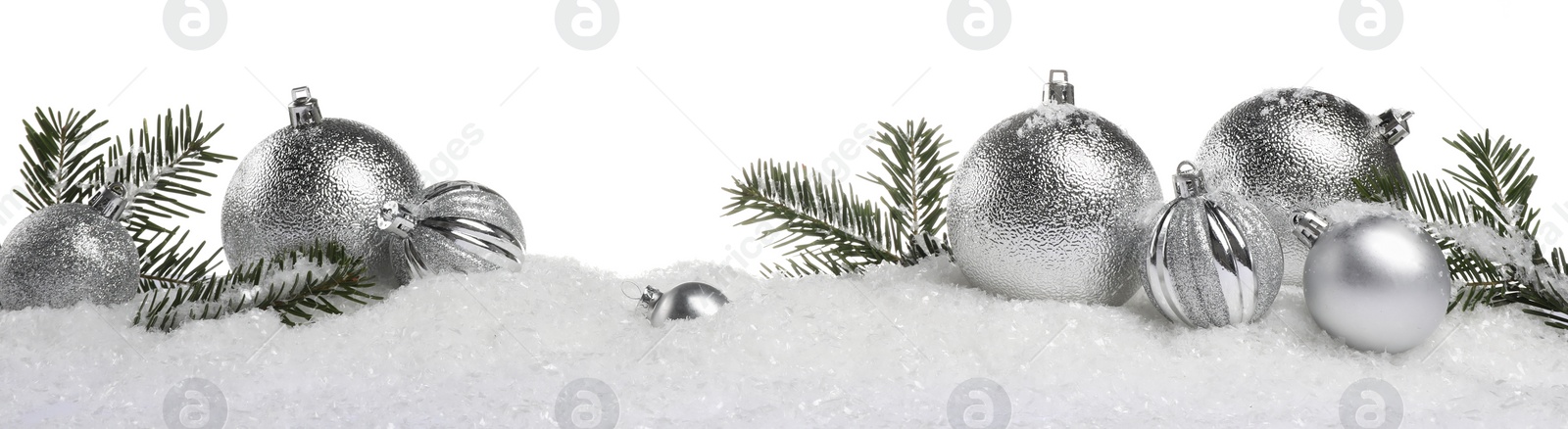 Photo of Beautiful silver Christmas balls and fir tree branches on snow against white background