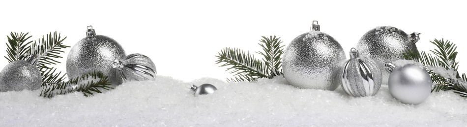 Beautiful silver Christmas balls and fir tree branches on snow against white background