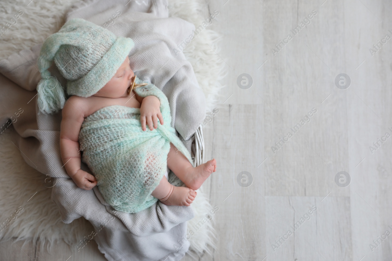 Photo of Cute newborn baby sleeping on plaid in basket, top view. Space for text