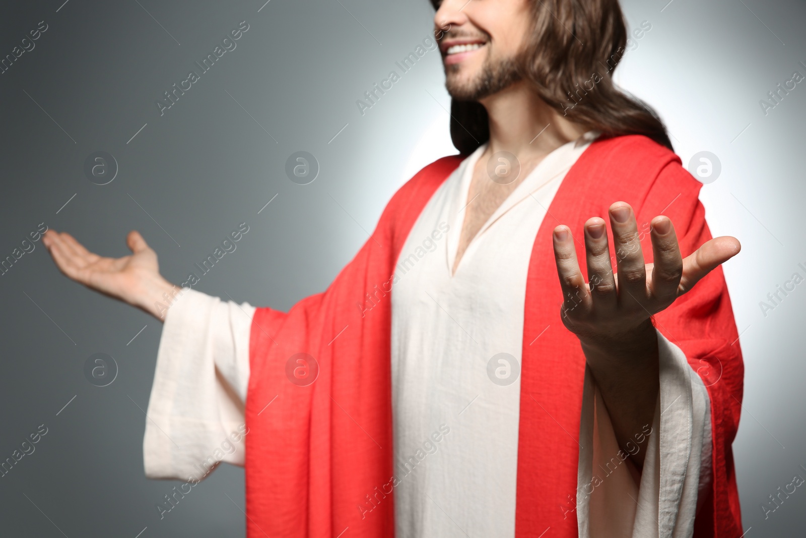 Photo of Jesus Christ reaching out his hands on grey background, closeup