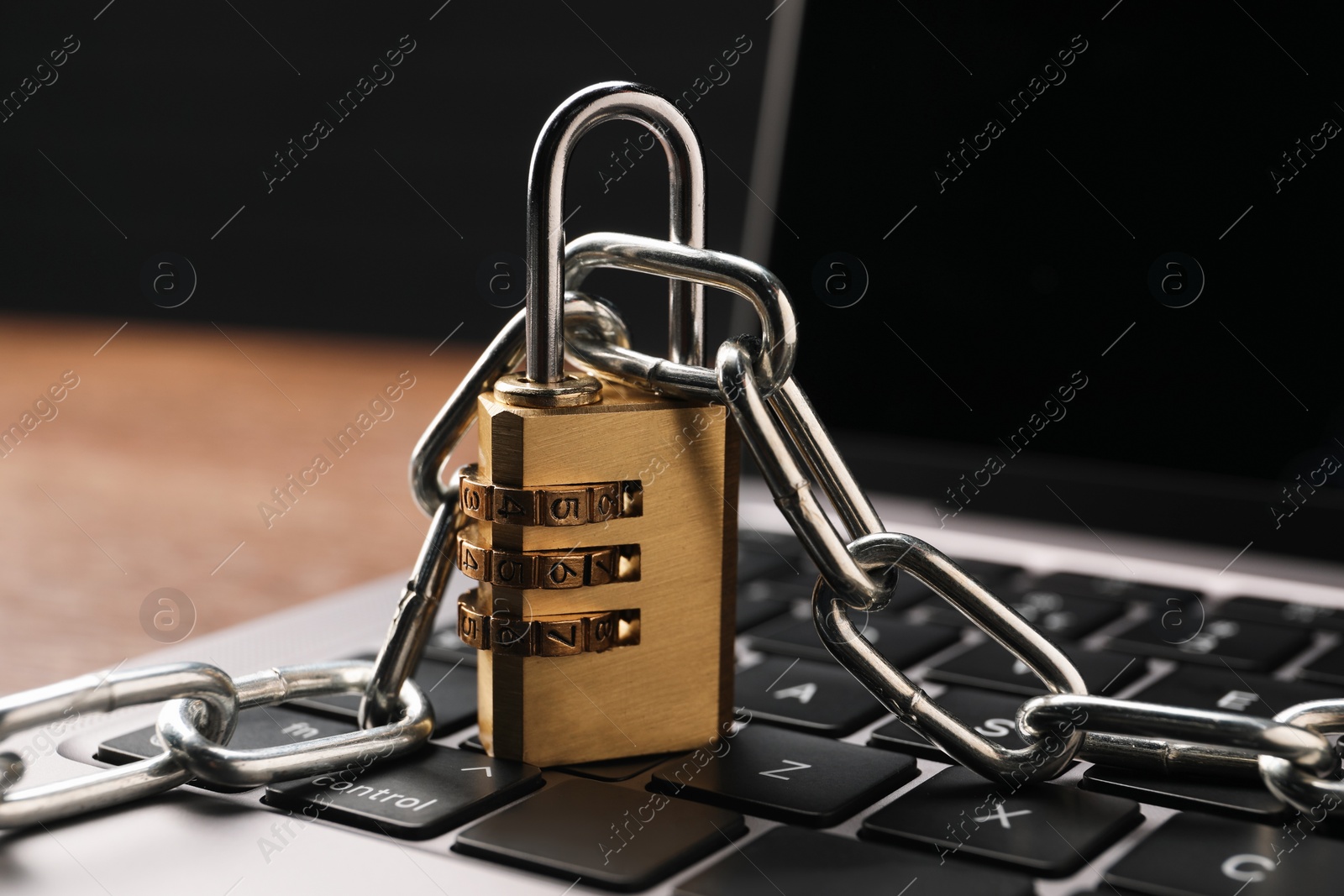 Photo of Cyber security. Laptop with padlock and chain on table, closeup