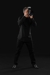 Photo of Professional photographer taking picture on black background