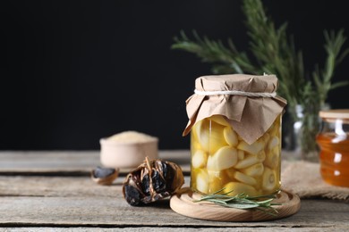 Photo of Garlic with honey in glass jar and fermented black garlic on wooden table. Space for text