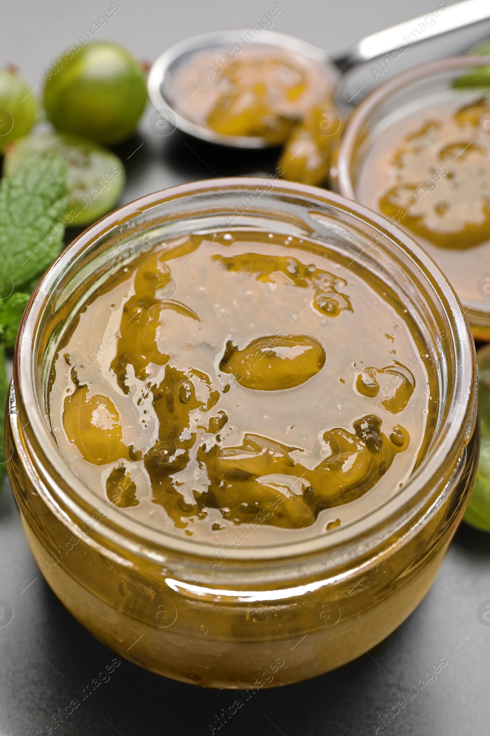 Photo of Jar of delicious gooseberry jam on table, closeup