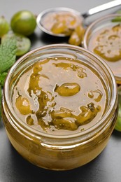 Jar of delicious gooseberry jam on table, closeup