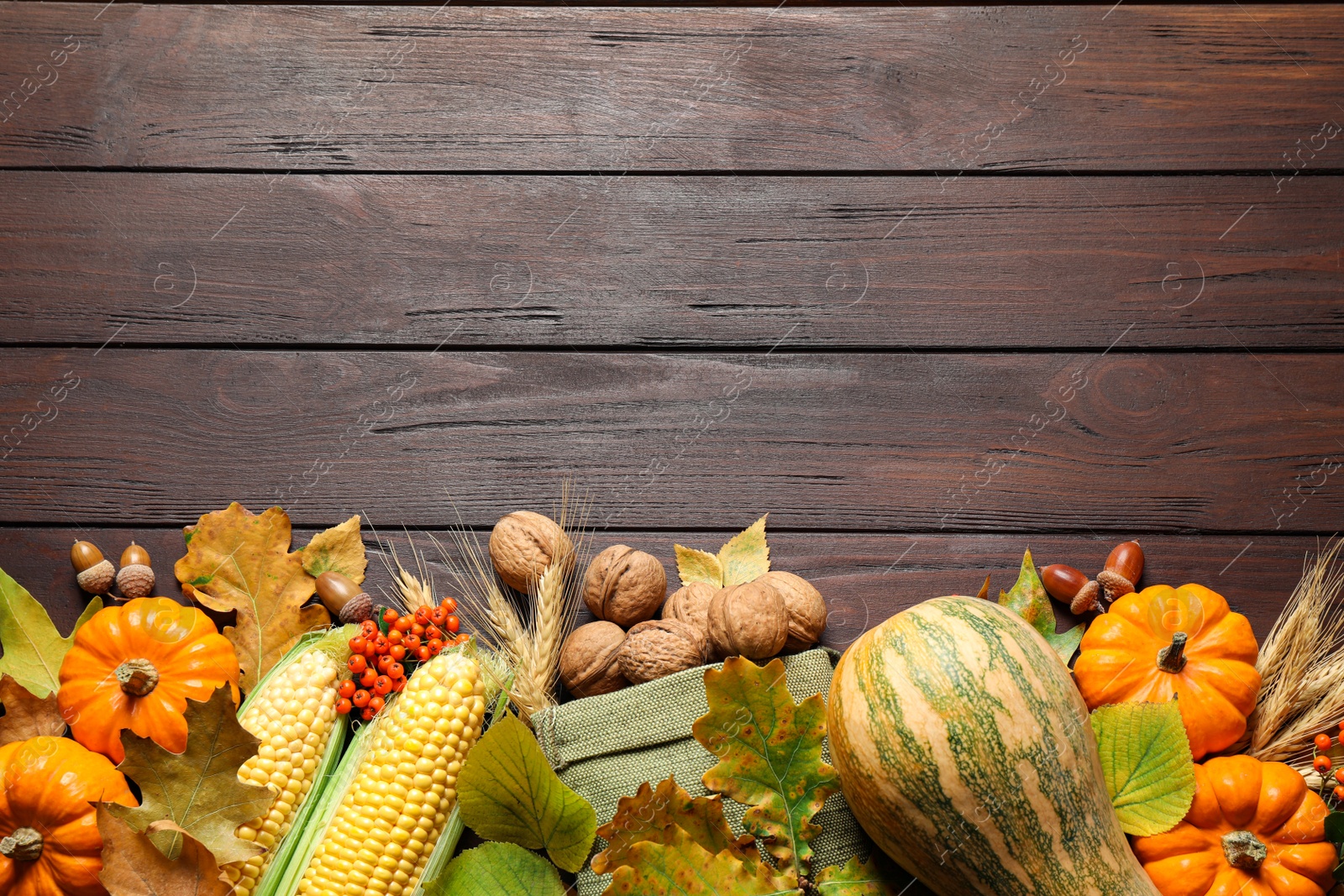 Photo of Flat lay composition with vegetables, nuts and autumn leaves on wooden table, space for text. Thanksgiving Day