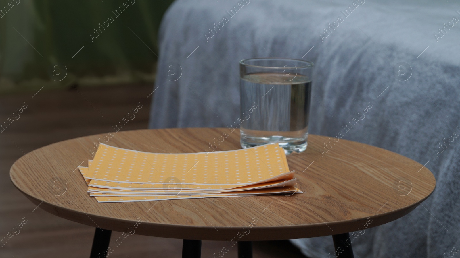 Photo of Pepper plasters and glass of water on wooden coffee table indoors
