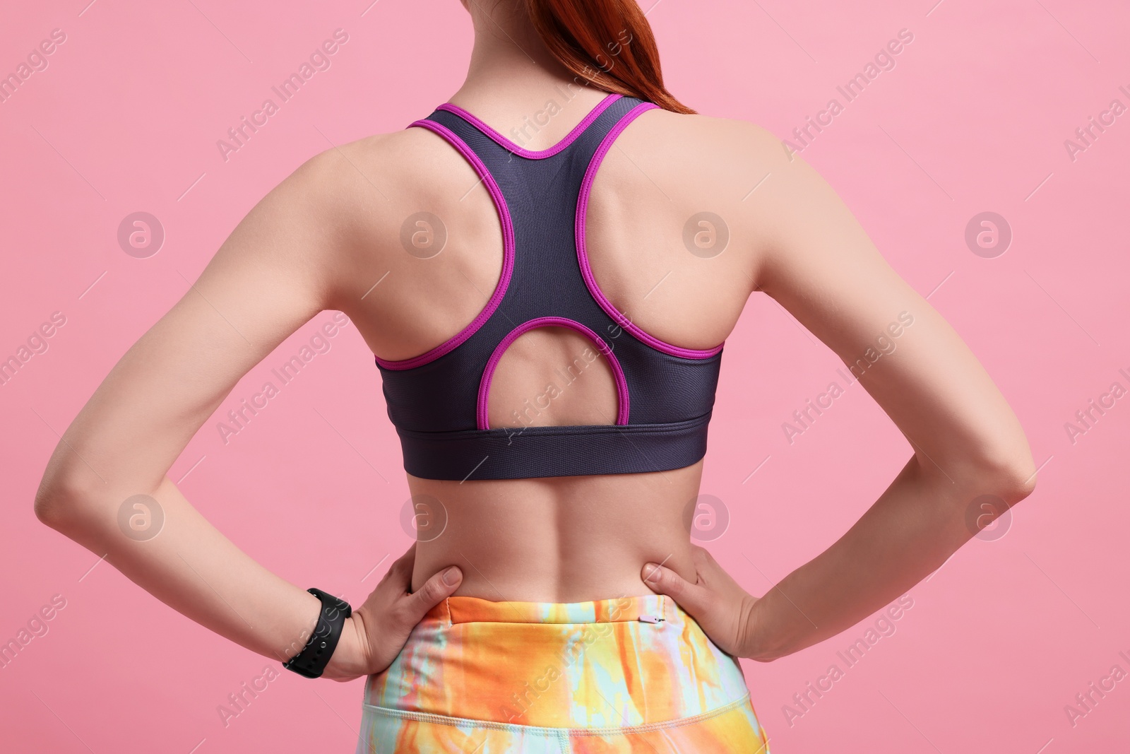 Photo of Woman in sportswear on pink background, back view