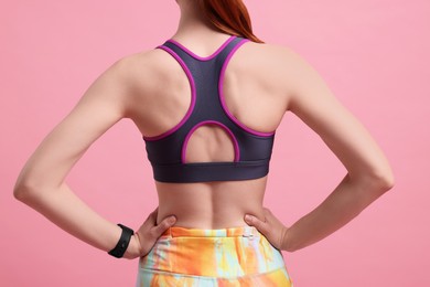 Photo of Woman in sportswear on pink background, back view