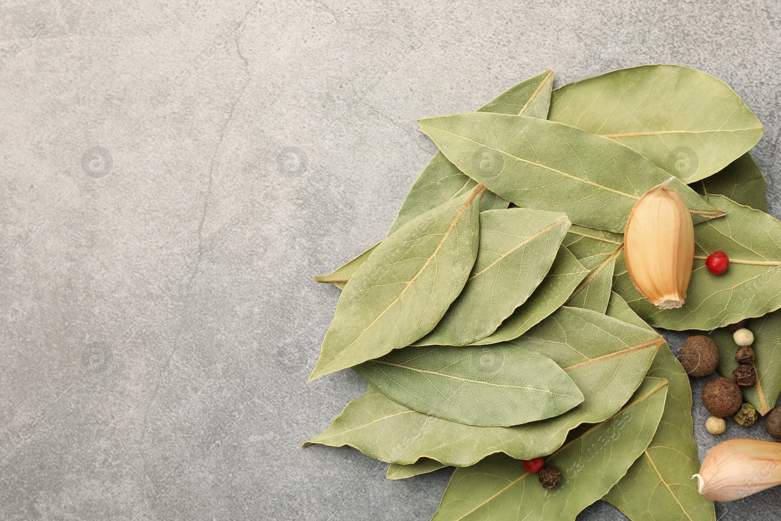 Photo of Aromatic bay leaves and spices on light gray table, flat lay. Space for text