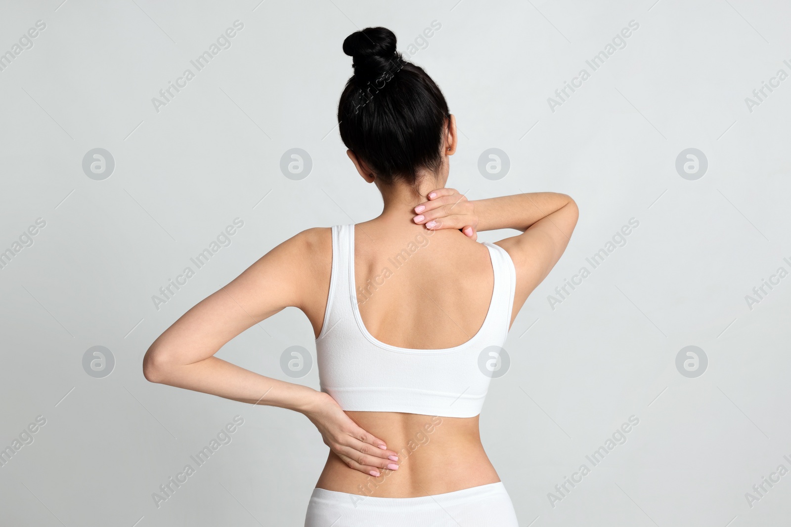 Photo of Woman suffering from pain in back on light background