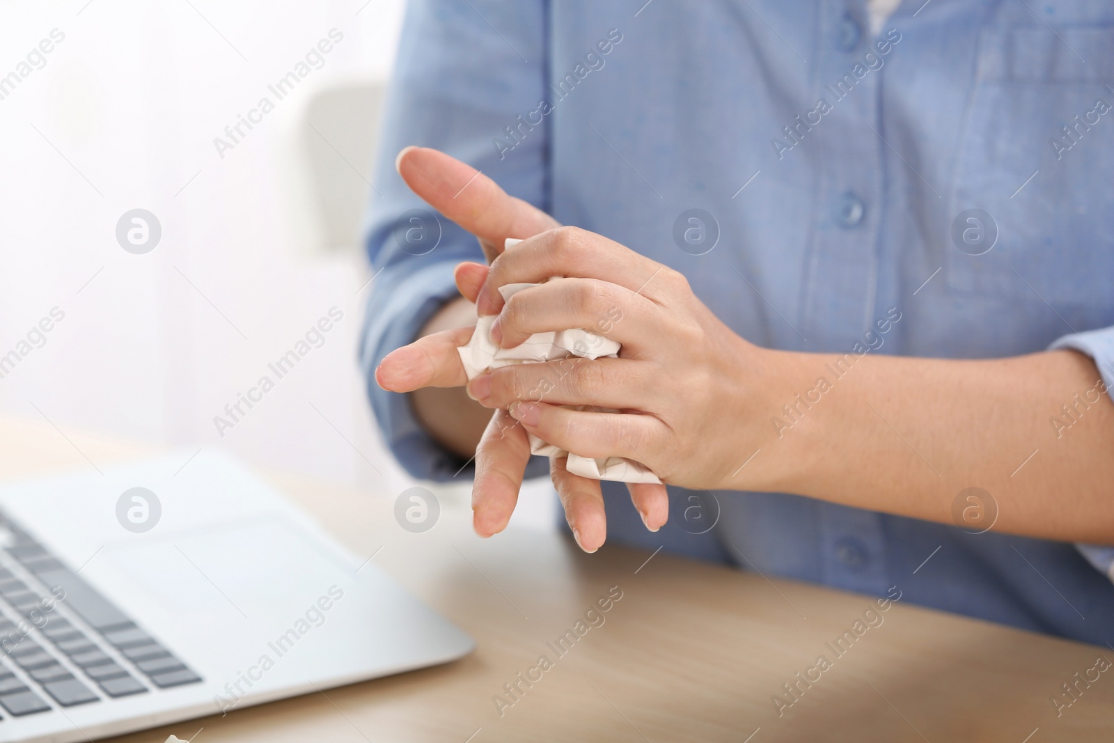 Photo of Woman crumpling paper at table, closeup. Generating idea