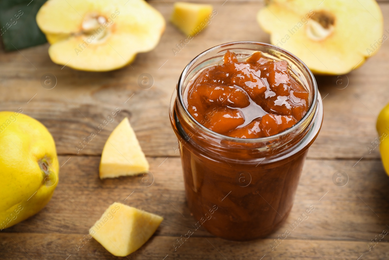 Photo of Delicious quince jam and fruits on wooden table