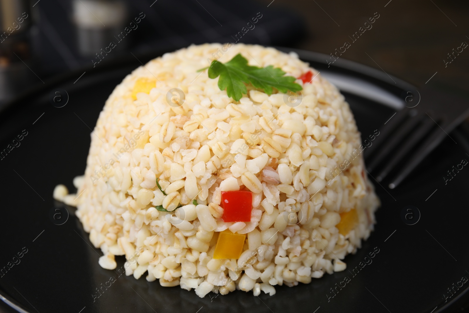 Photo of Delicious bulgur with vegetables and parsley on table, closeup