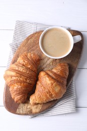 Photo of Tasty breakfast. Cup of coffee and croissants on white wooden table, top view