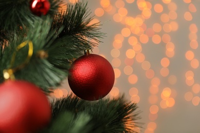 Photo of Red holiday bauble hanging on Christmas tree against blurred festive lights, closeup. Space for text