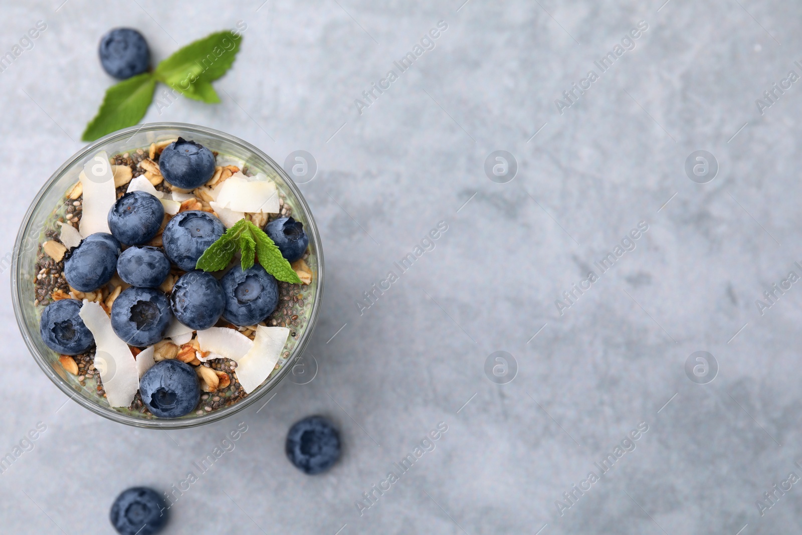 Photo of Tasty oatmeal with smoothie, blueberries, coconut and mint on grey table, flat lay. Space for text. Healthy breakfast