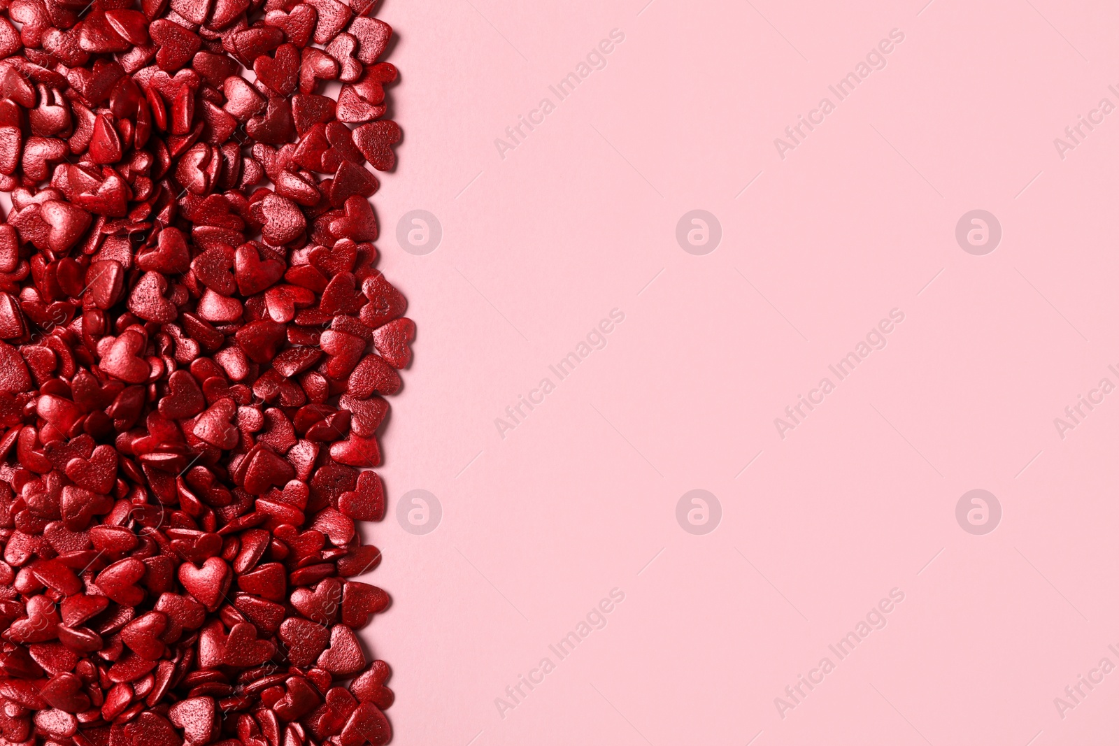 Photo of Red heart shaped sprinkles on pink background, flat lay. Space for text