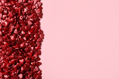Red heart shaped sprinkles on pink background, flat lay. Space for text