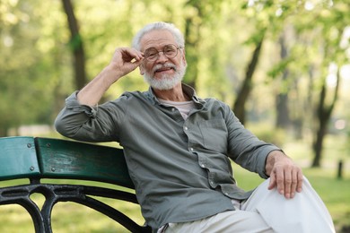 Portrait of happy grandpa with glasses on bench in park