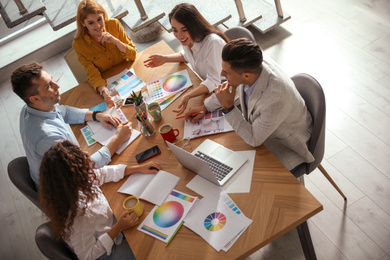 Photo of Team of professional designers working together at table in office