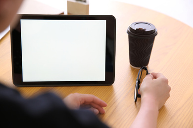 Woman working with modern tablet at wooden table, closeup. Space for design