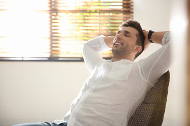 Photo of Young man relaxing near window at home. Space for text