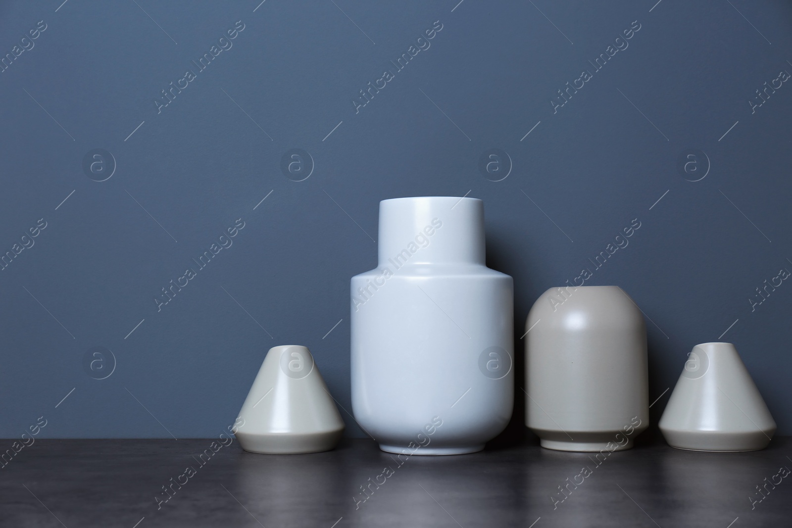 Photo of Beautiful ceramic vases on table against color wall with space for text