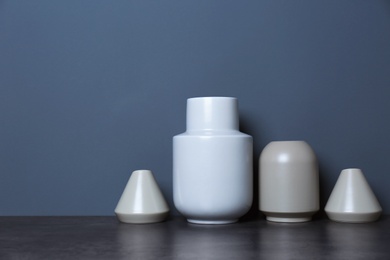 Beautiful ceramic vases on table against color wall with space for text