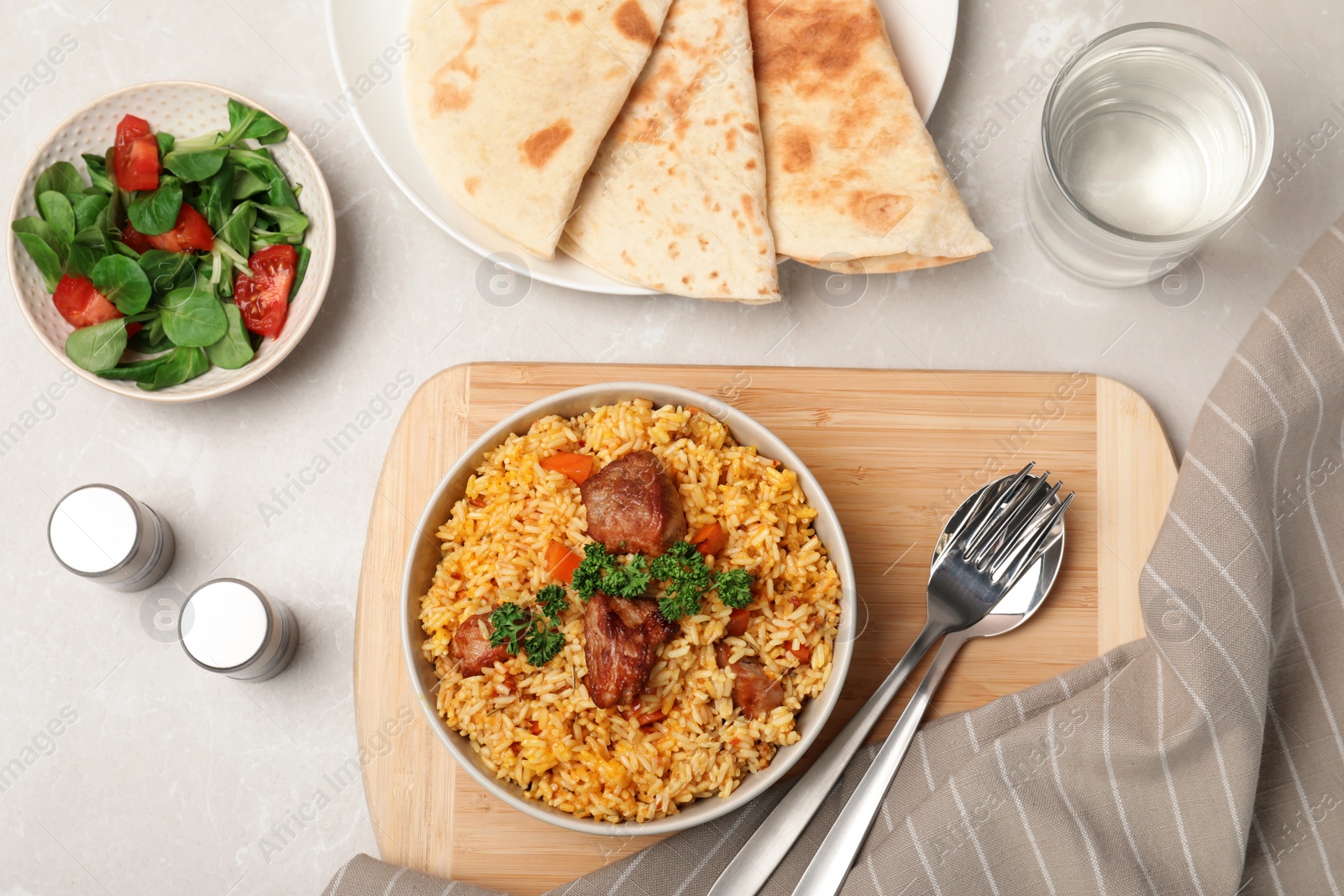 Photo of Flat lay composition with bowl of rice pilaf, salad and pita on table