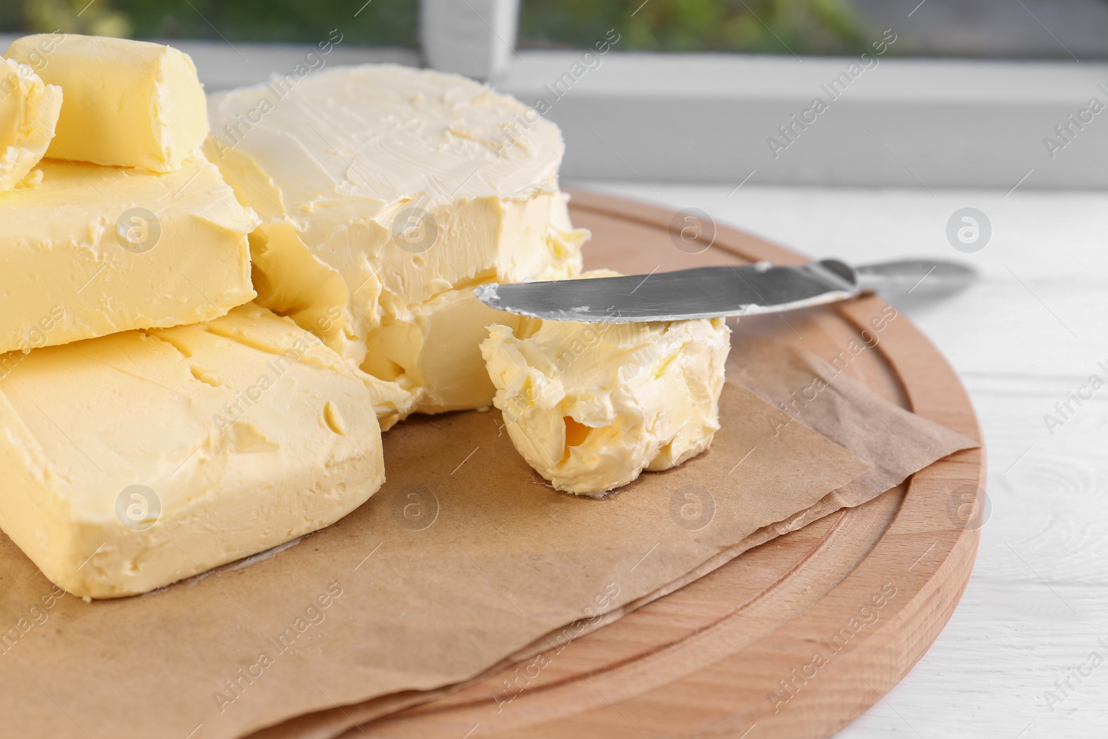 Photo of Tray with tasty homemade butter and knife on white wooden windowsill, closeup