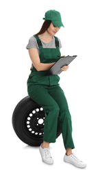Professional auto mechanic with wheel and clipboard on white background