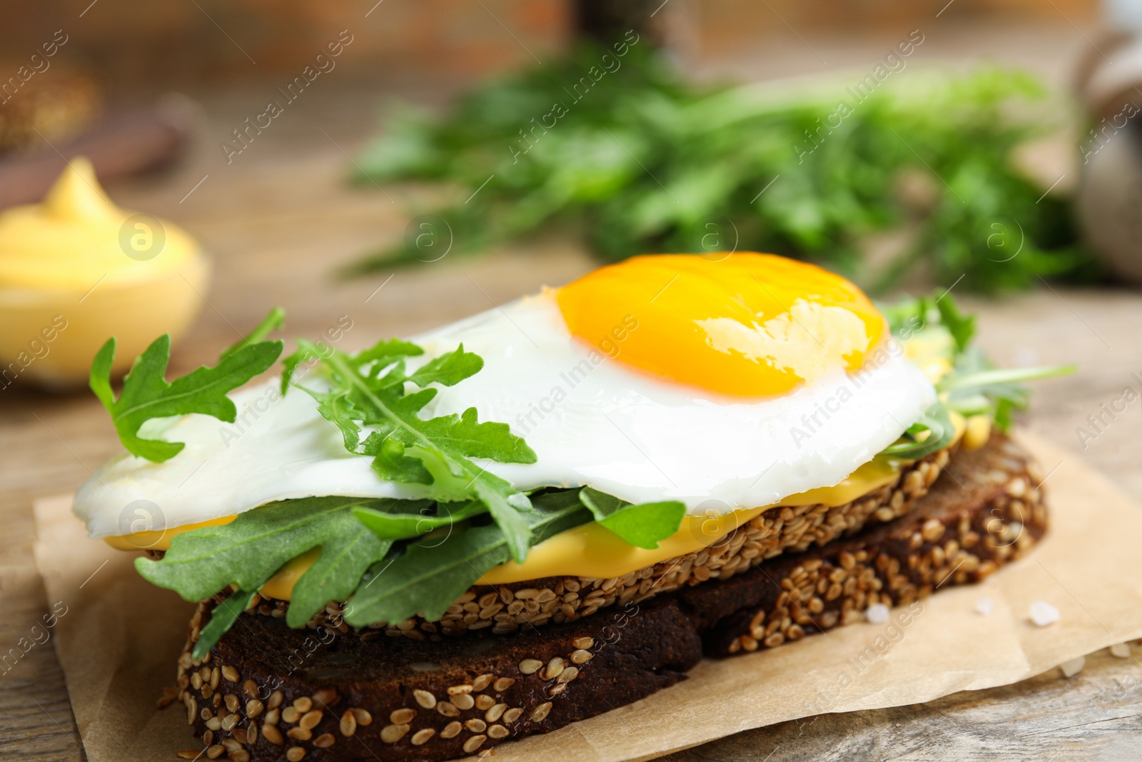 Photo of Delicious sandwich with arugula and egg on wooden table, closeup