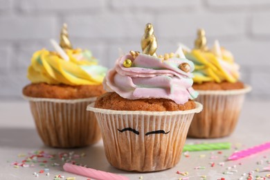 Photo of Cute sweet unicorn cupcakes on beige table, closeup
