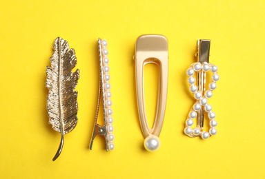 Photo of Stylish hair clips on yellow background, flat lay