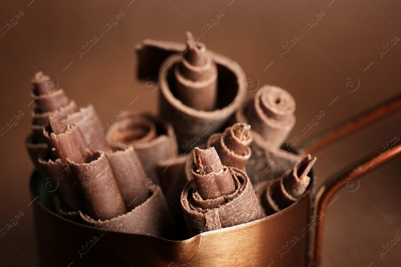 Photo of Pan with chocolate curls on color background, closeup