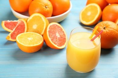 Photo of Delicious orange juice and fresh fruits on light blue wooden table