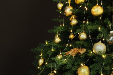 Photo of Beautifully decorated Christmas tree on brown background, closeup. Space for text
