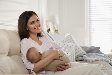 Young woman with her sleeping baby on sofa at home