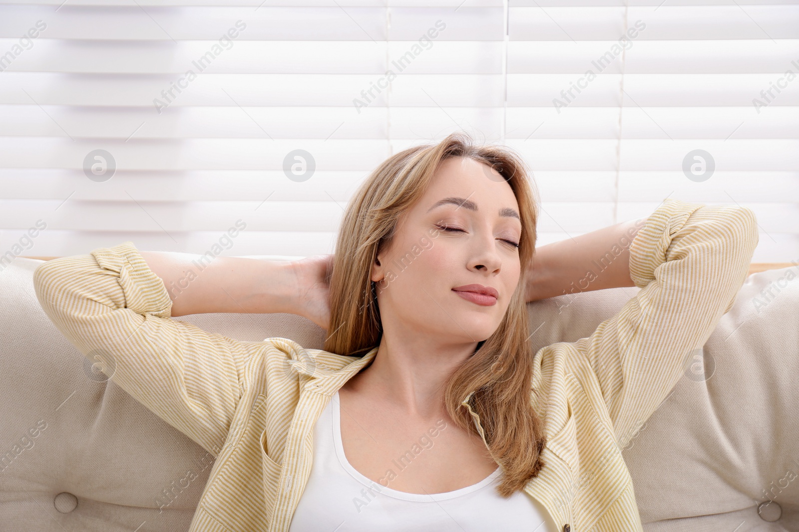 Photo of Beautiful young woman relaxing on sofa indoors