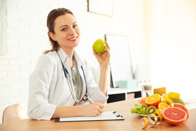 Image of Nutritionist with apple and clipboard at desk in office