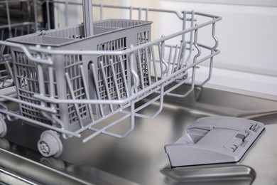 Photo of Open clean empty dishwasher in kitchen, closeup