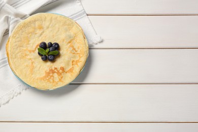 Photo of Stack of delicious crepes with mint and fresh berries on white wooden table, top view. Space for text