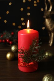 Photo of Red burning candle and Christmas decor on wooden table