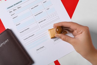 Photo of Immigration to Canada. Woman stamping visa application form on flag, top view