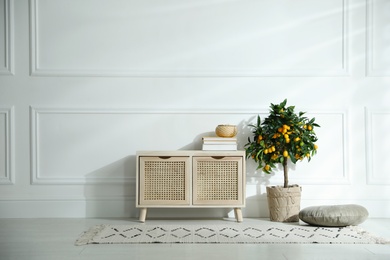 Photo of Wooden commode near white wall in room. Interior design