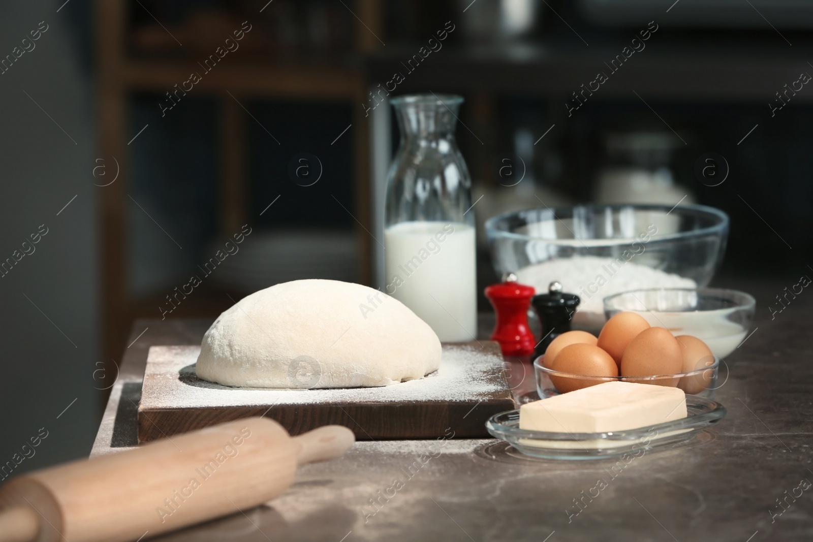 Photo of Dough covered with flour and ingredients on table in kitchen