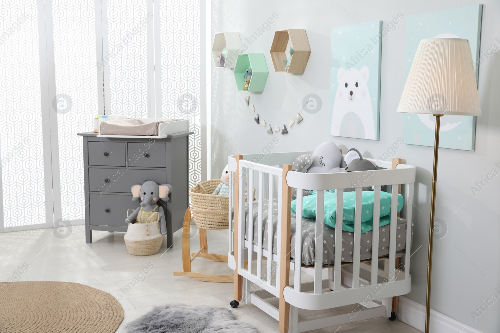 Photo of Cozy baby room with crib and other furniture. Interior design