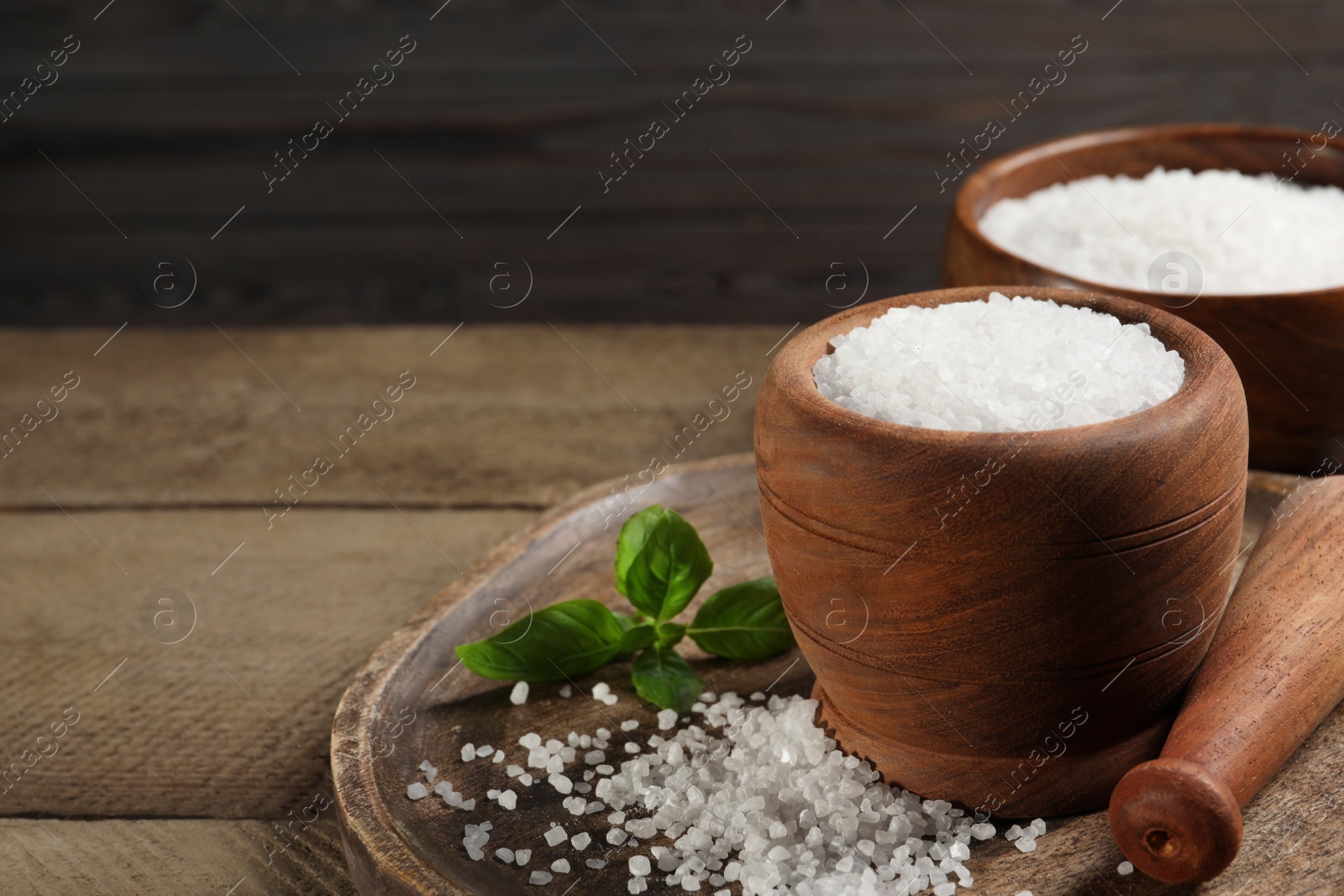 Photo of Pestle and mortar with natural sea salt on wooden table