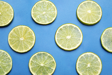 Photo of Juicy fresh lime slices on blue background, flat lay